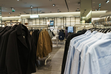 Fashionable clothes on hangers in a store.