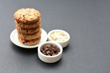Oatmeal cookies and chocolate chips on black background
