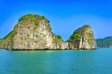 Naklejka premium Halong bay islands. Tourist attraction, spectacular limestone grottos natural cave formations. Karst landforms in the sea, the world natural heritage. Beautiful azure water of the lagoon.
