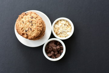 Oatmeal cookies and chocolate chips on black background