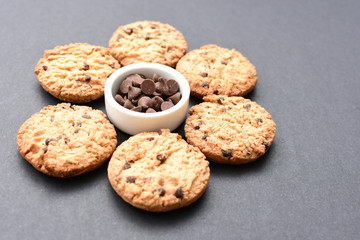 Oatmeal cookies and chocolate chips on black background