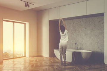 Woman in white loft bathroom with tub