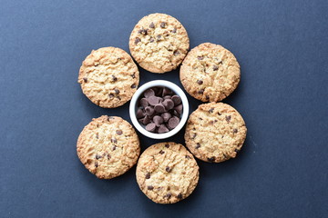 Oatmeal cookies and chocolate chips on black background