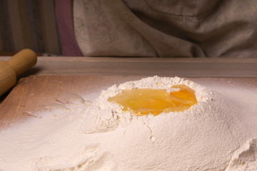 Flour sprinkled on a table with an egg for making dough.