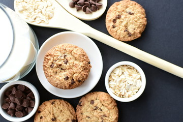 Oatmeal cookies and chocolate chips on black background