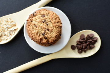 Oatmeal cookies and chocolate chips on black background