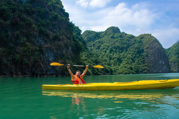 Happy bearded man rowing kayak in Ha Long Bay. Halong bay is popular tourist attraction in Vietnam for leisure and sport activities.