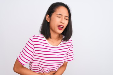 Fototapeta premium Young chinese woman wearing striped t-shirt standing over isolated white background with hand on stomach because indigestion, painful illness feeling unwell. Ache concept.