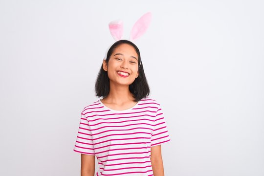 Young beautiful chinese woman wearing banny ears standing over isolated white background with a happy face standing and smiling with a confident smile showing teeth