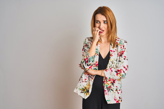 Young caucasian business woman wearing spring floral jacket suit over isolated background looking stressed and nervous with hands on mouth biting nails. Anxiety problem.