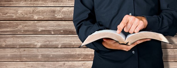 Man reading the old heavy book on wooden background