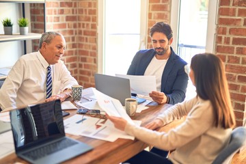 Group of business workers working together. Sitting on desk using laptop reading documents at the office