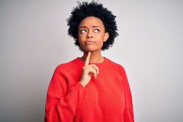 Obraz na płótnie Canvas Young beautiful African American afro woman with curly hair wearing red casual sweater Thinking concentrated about doubt with finger on chin and looking up wondering