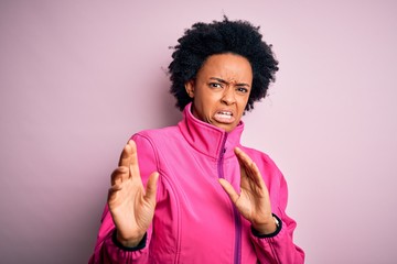 Fototapeta na wymiar Young African American afro sportswoman with curly hair wearing sportswear doin sport disgusted expression, displeased and fearful doing disgust face because aversion reaction. With hands raised