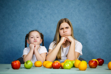 Fototapeta na wymiar Little girl and mom play with fruits and fool around. They are wearing t-shirts