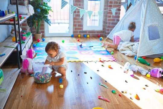 Beautiful toddlers playing around lots of toys at kindergarten