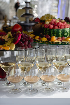 Vertical images of alcoholic cocktails on festive table with watermelon, grape, pitahaya, carambola, banana and different fresh fruits. Celebration or other event