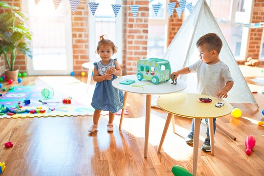 Adorable toddlers smiling happy. Standing playing around lots of toys at kindergarten