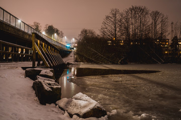 Drweniany mały mostek na zamarźniętym jeziorze w mroźny zimowy wieczór