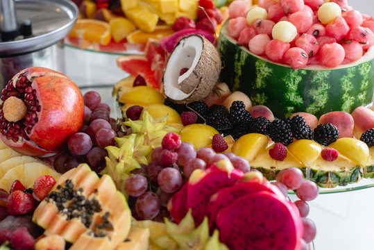 Horizontal images of festive table different fresh fruits with pineapple, coconut, grapes, berries, watermelon, apples, pomegranate. Celebration or other event