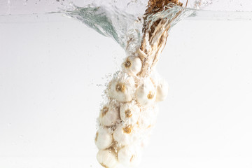 garlic falls into water over white background