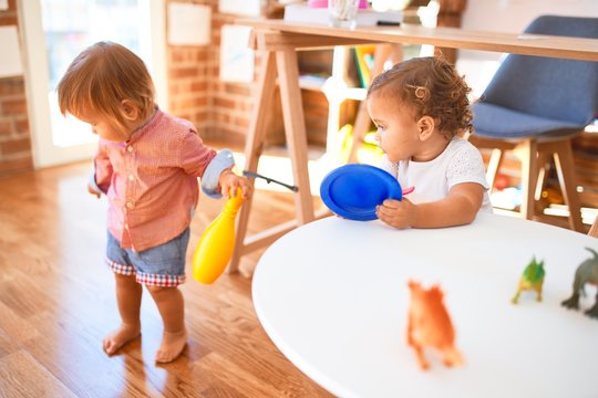 Adorable toddlers playing around lots of toys at kindergarten