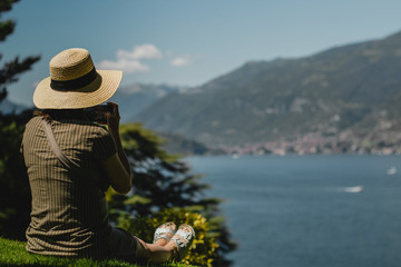 Obraz premium Healthy woman celebrating during a beautiful sunset. Happy and Free. Young woman sits at lake, at seaside looking at mountains and taking shots of picturesque view. 