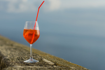 Aperol spritz with straw and ice cubes on the balcony 