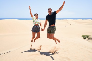 Young beautiful couple smiling happy and confident. Jumping with smile on face at the beach