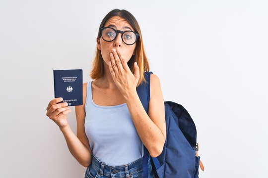 Beautiful redhead student woman wearing backpack and holding passport of germany cover mouth with hand shocked with shame for mistake, expression of fear, scared in silence, secret concept