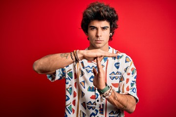 Young handsome man on vacation wearing summer shirt over isolated red background Doing time out...