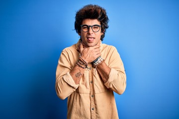 Young handsome man wearing casual shirt standing over isolated blue background shouting and suffocate because painful strangle. Health problem. Asphyxiate and suicide concept.