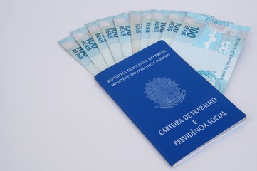 Brazilian work card and social security document (carteira de trabalho) with Brazilian money on white background. Work concept.