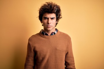 Young handsome man wearing casual shirt and sweater over isolated yellow background skeptic and nervous, frowning upset because of problem. Negative person.