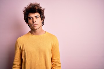 Fototapeta na wymiar Young handsome man wearing yellow casual t-shirt standing over isolated pink background Relaxed with serious expression on face. Simple and natural looking at the camera.