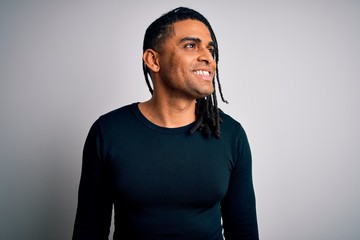 Young handsome african american man with dreadlocks wearing black casual sweater looking away to side with smile on face, natural expression. Laughing confident.