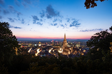 Naklejka premium Panorama der Skyline von Freiburg im Breisgau bei Nacht nach Sonnenuntergang mit rotem Himmel in magischer Dämmerung von oben