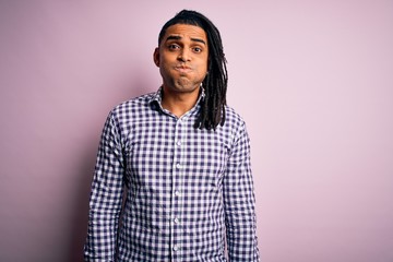 Obraz premium Young handsome african american afro man with dreadlocks wearing casual shirt puffing cheeks with funny face. Mouth inflated with air, crazy expression.
