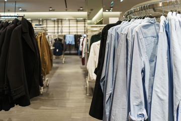 Fashionable clothes on hangers in a store.