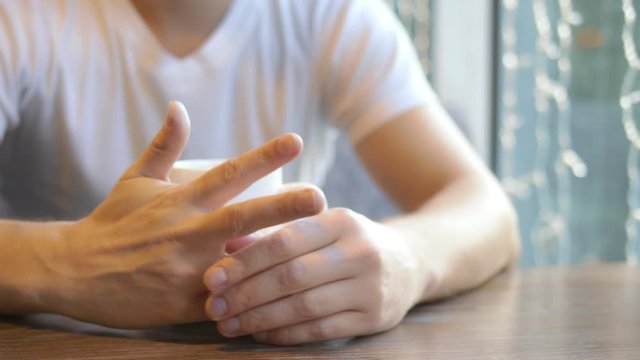 closeup. man takes off a wedding ring while sitting in a cafe.