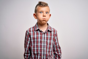 Young little caucasian kid with blue eyes wearing elegant shirt standing over isolated background puffing cheeks with funny face. Mouth inflated with air, crazy expression.