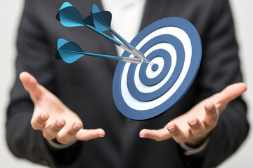 hand holding a target with darts hitting the center over white background. Concept of .
