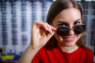 Girl picks up sunglasses. Eyeglasses shop. Vision correction. Glasses Stand