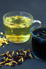 cup of hot herbal tea with dry flowers of Jasmine on a black table. Jasmine tea. Hot drinks. Healthy lifestyle. glass cup of Jasmine tea on a black background. vertical orientation