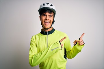Young handsome cyclist man wearing security bike helmet over isolated white background smiling and looking at the camera pointing with two hands and fingers to the side.