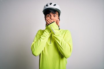 Young handsome cyclist man wearing security bike helmet over isolated white background shocked covering mouth with hands for mistake. Secret concept.