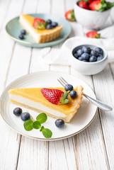 Cream cheese tart slices with lemon curd topping, served with fresh blueberries and strawberries