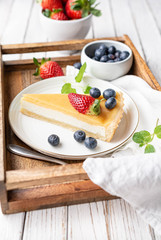 Cream cheese tart slices with lemon curd topping, served with fresh blueberries and strawberries