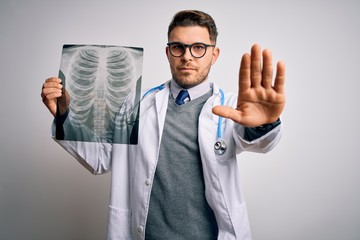 Young doctor man wearing medical coat looking at chest scan radiography over isolated background...