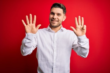 Young business man with blue eyes wearing elegant shirt standing over red isolated background showing and pointing up with fingers number nine while smiling confident and happy.